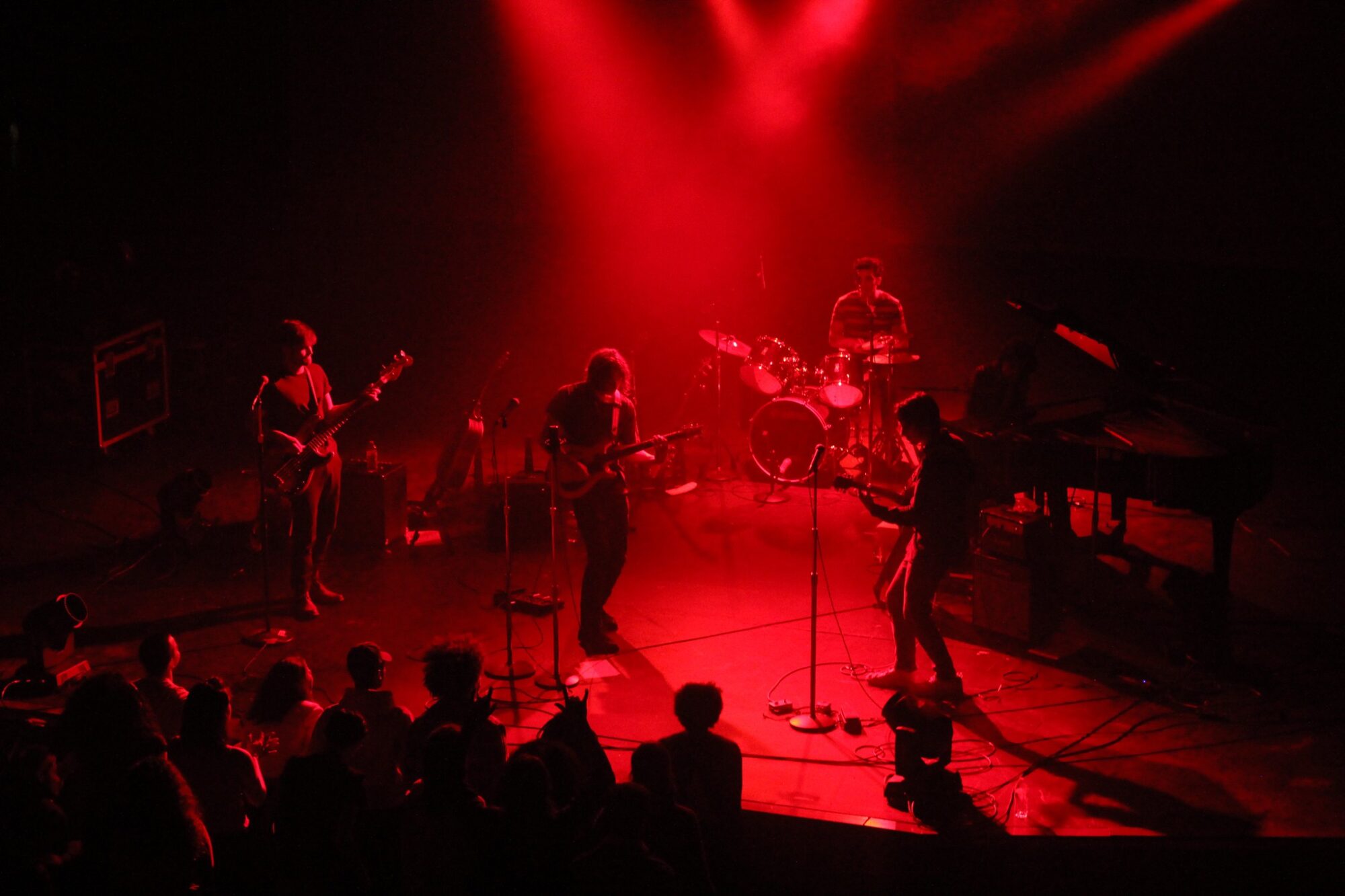 Red light illuminates a stage with a rock band playing.