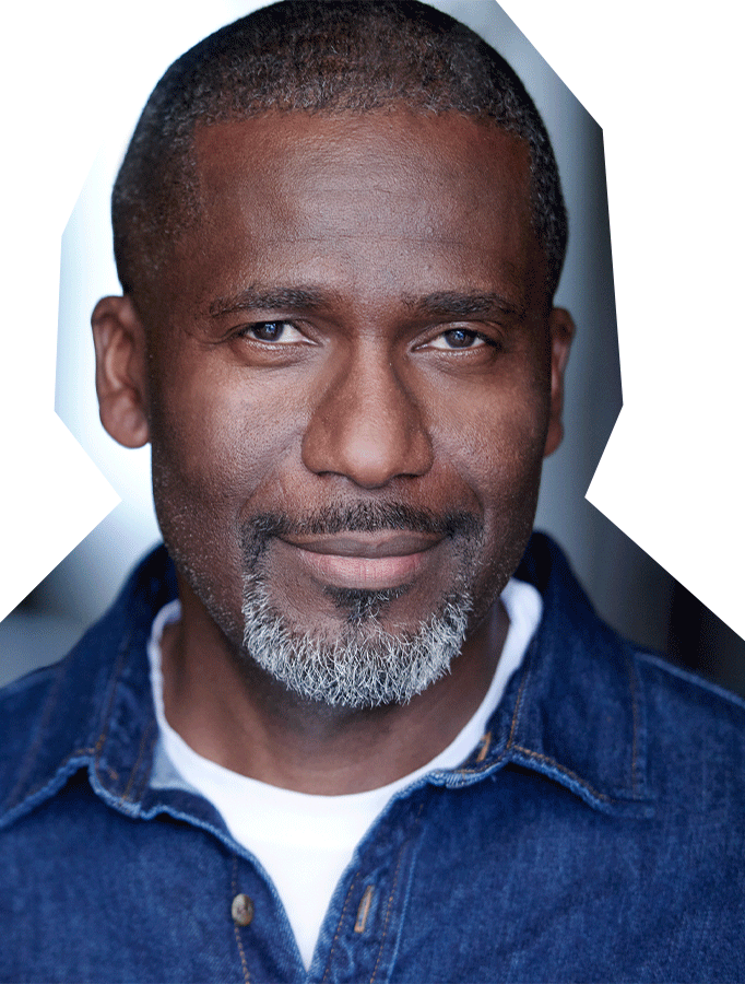 Photo of Ausar Stewart, a black man wearing a denim collared shirt with a white tee shirt underneath.