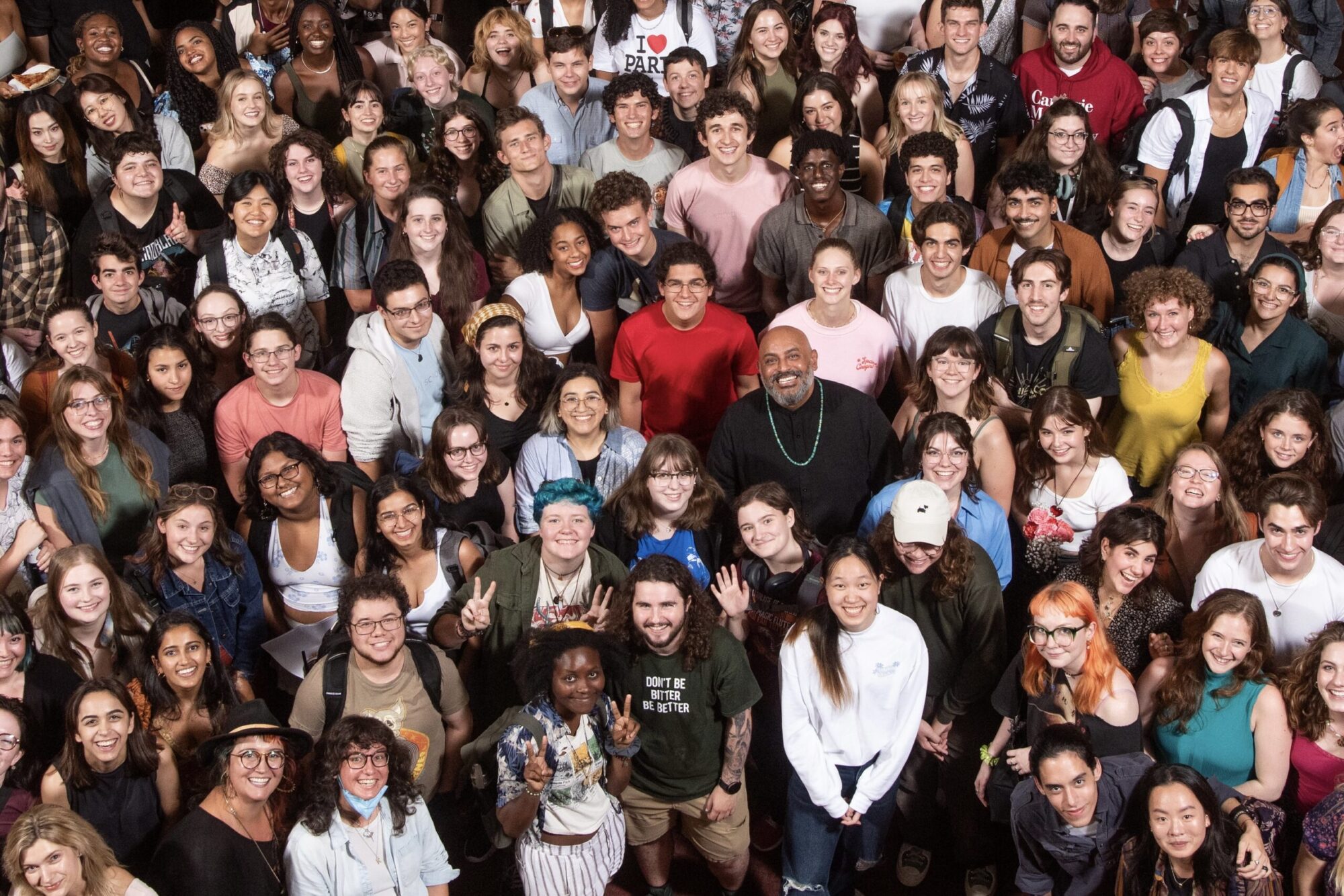 A photo taken from above of a large group of students in the lobby of the Purnell Center for the Arts looking up and smiling.