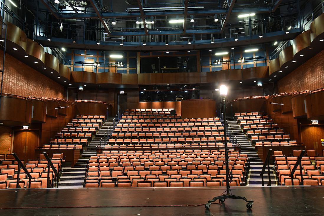 Photo taken from the stage of the Philip Chosky Theater, looking into the 400-seat audience; a ghost light is on on the stage.