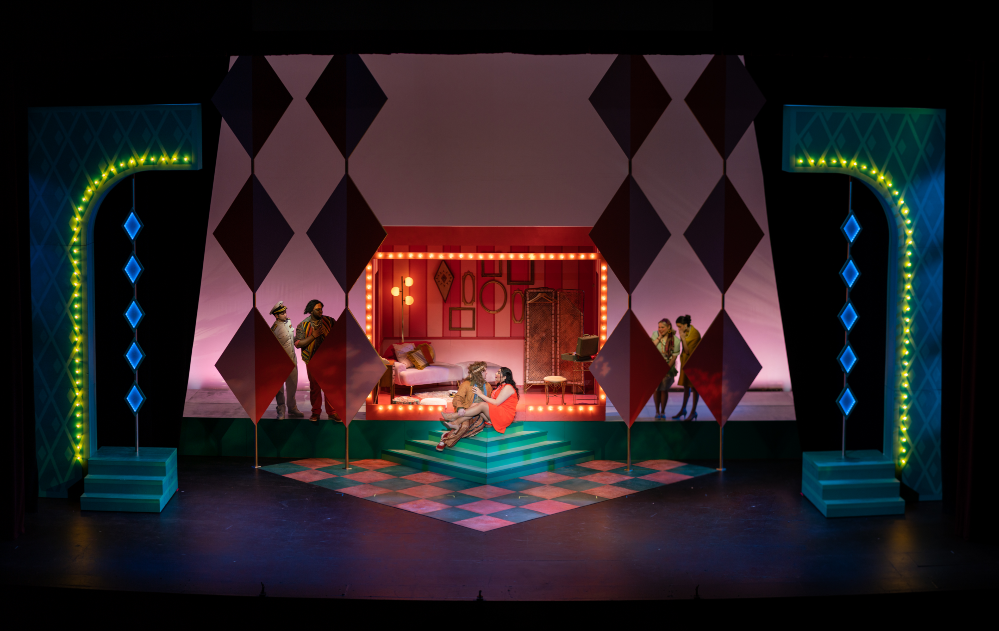 A brightly and colorfully lit stage with a scene from the School of Music’s opera “Cosi Fan Tutte.”