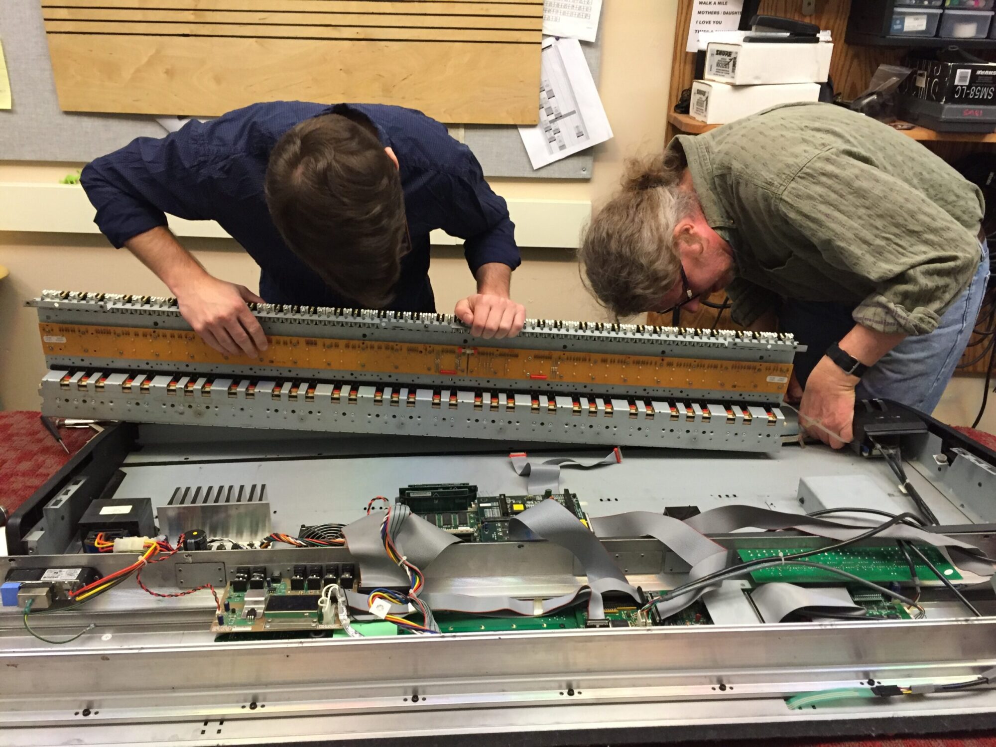 A student and professor hold a deconstructed keyboard up as they make repairs.