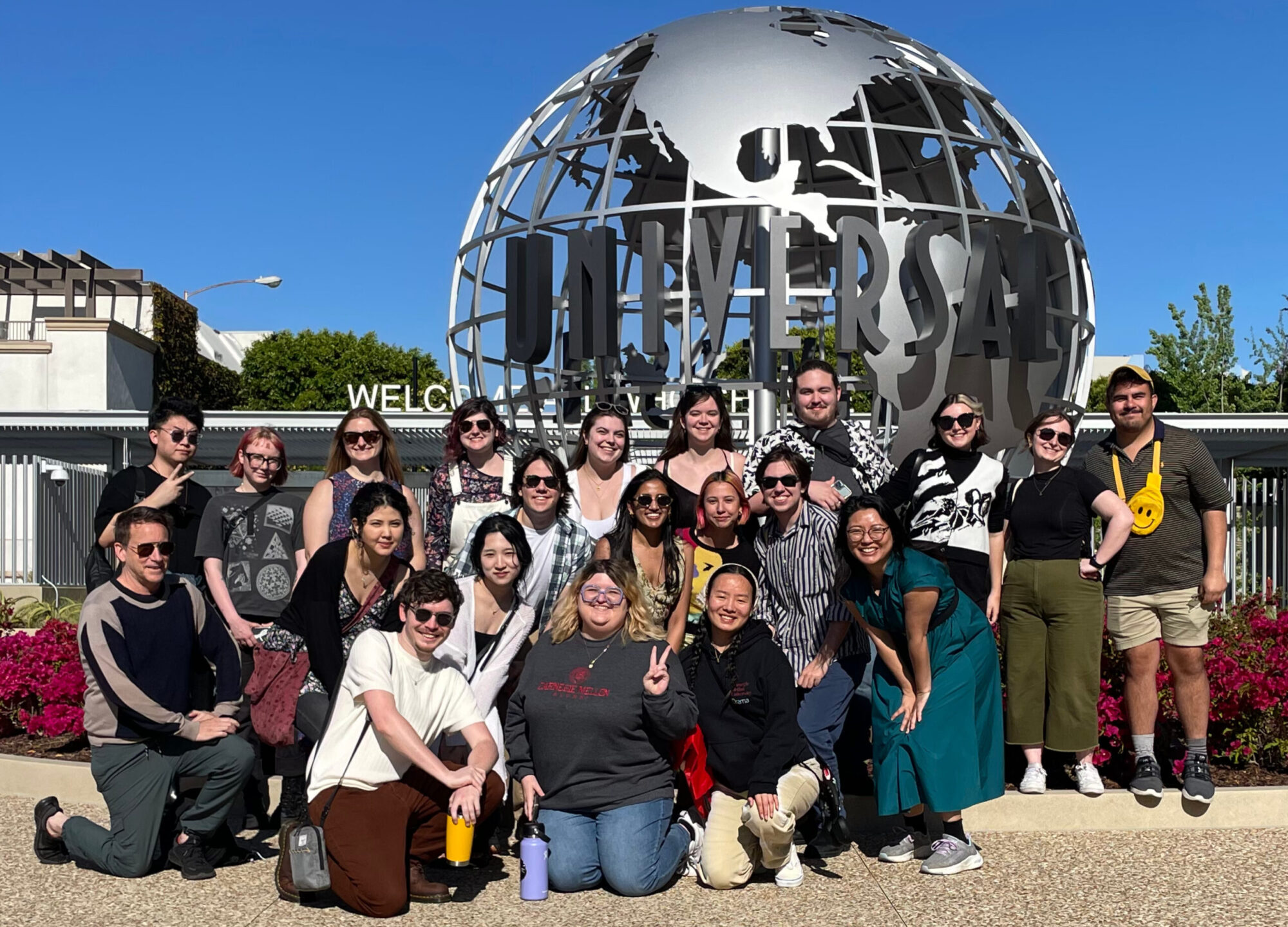 A group of students poses, smiling in front of the large Universal Studios silver globe sculpture.