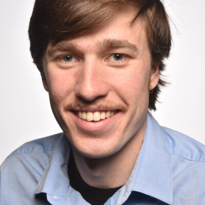 Headshot of Owen Sahnow, wearing a light blue collared shirt, smiling at the camera.