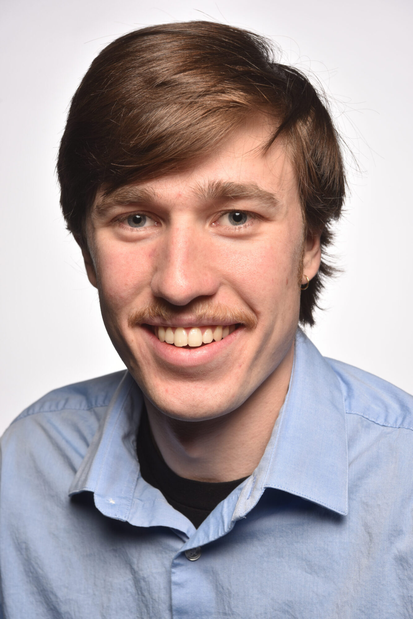 Headshot of Owen Sahnow, wearing a light blue collared shirt, smiling at the camera.