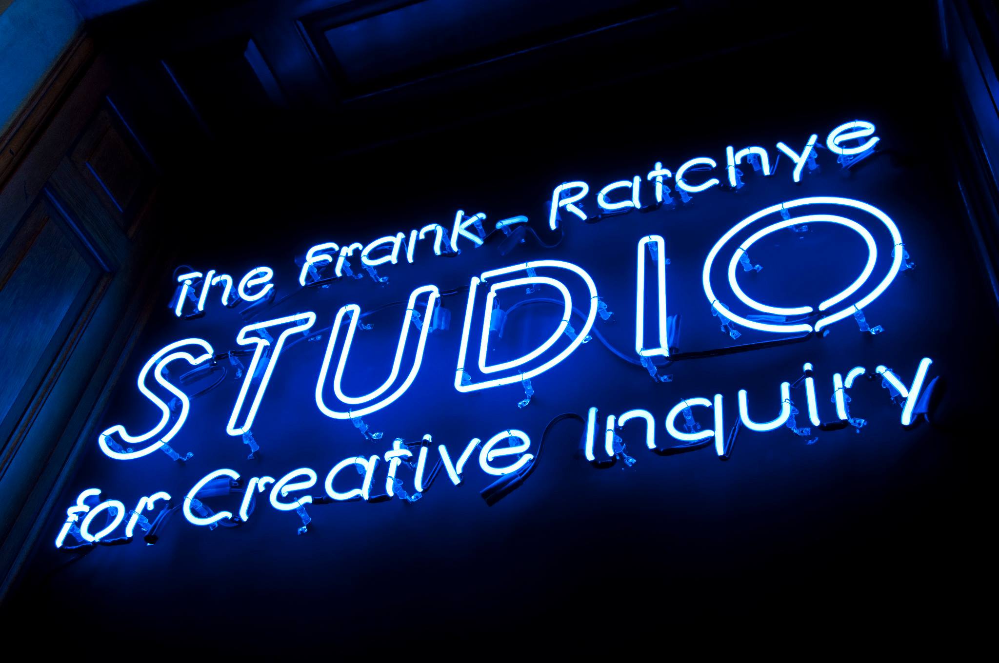 A blue neon sign that reads: The Frank-Ratchye STUDIO for Creative Inquiry