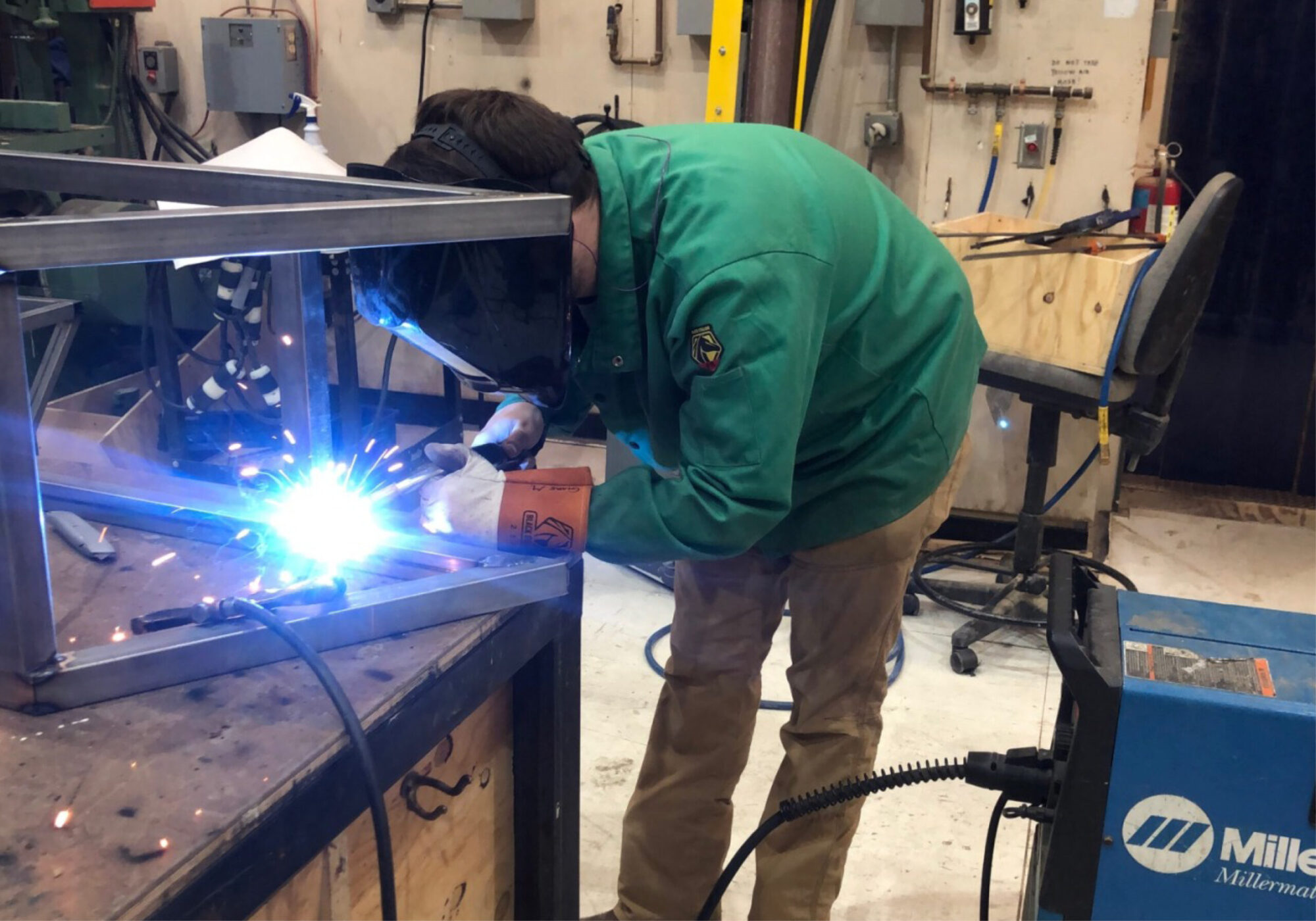 A student wears a protective mask and uses welding equipment in the School of Drama’s scene shop.