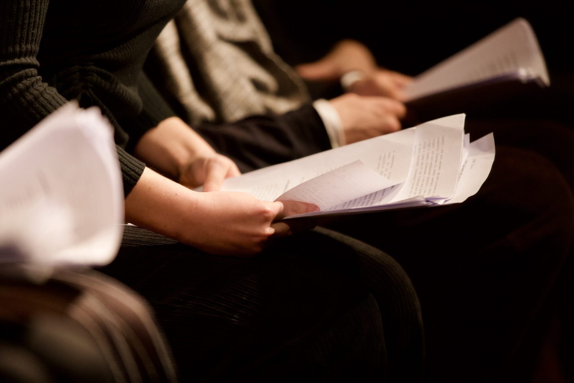 A close up on hands holding several sheets of white paper.