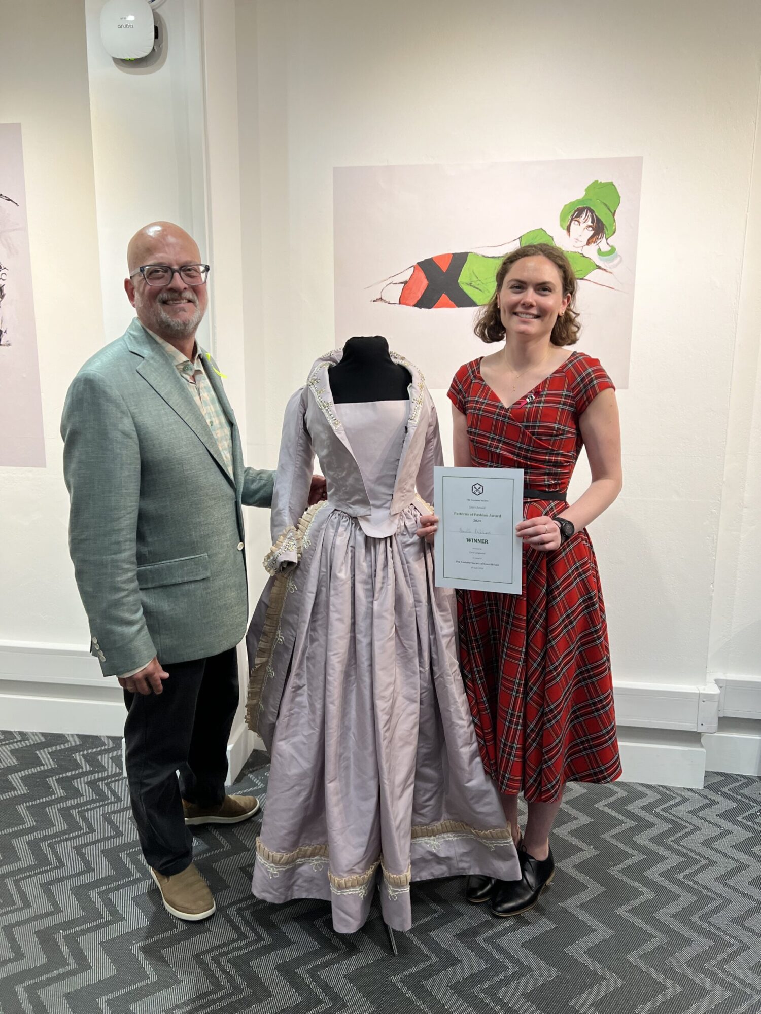 Hugh Hanson (faculty) and Danielle Dulchinos (recent grad) stand with a dress form wearing Danielle’s thesis project - a hand-sewn and hand-embroidered re-creation of an 18th century gown and petticoat.