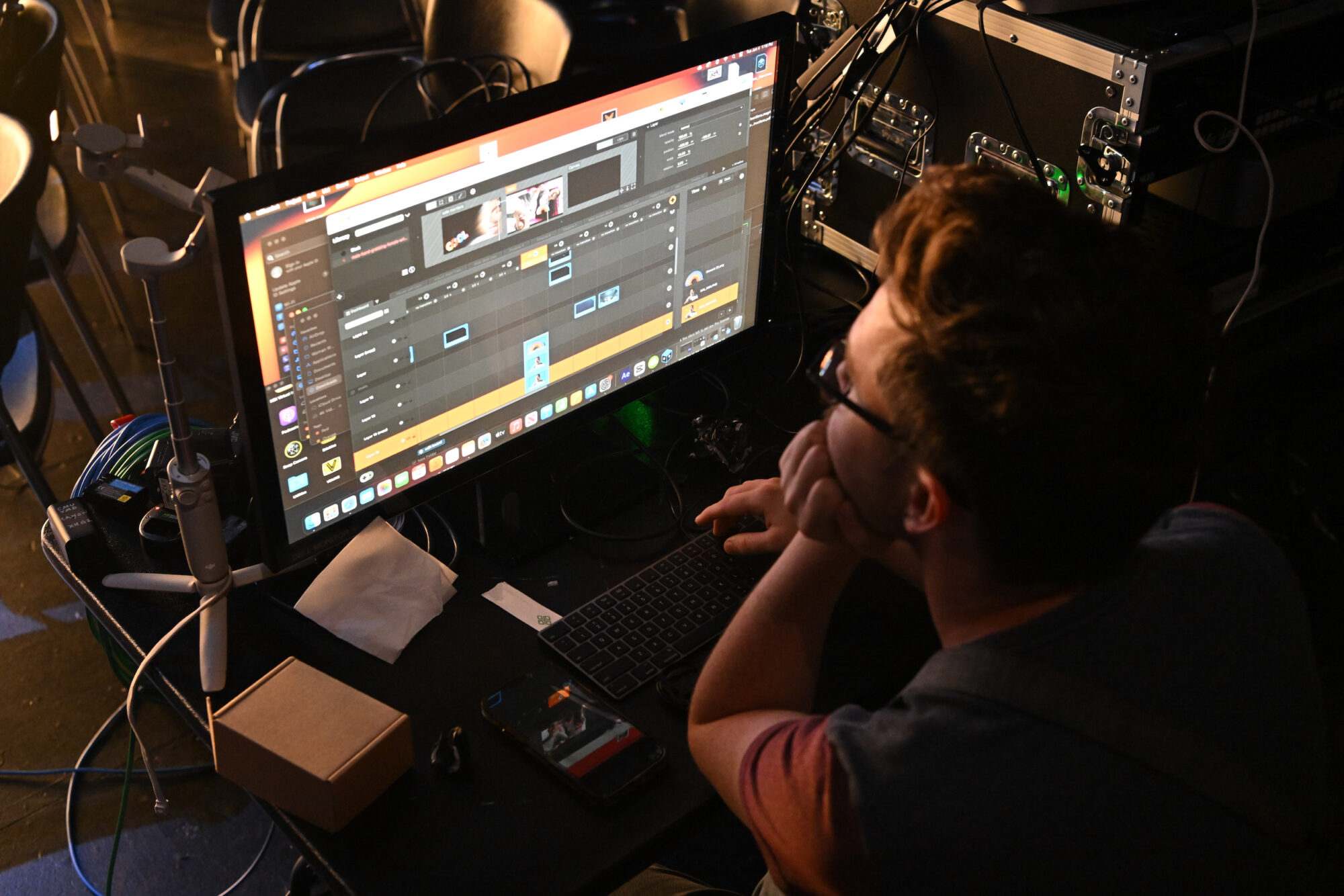 A person sits looking at a computer screen running a media program.