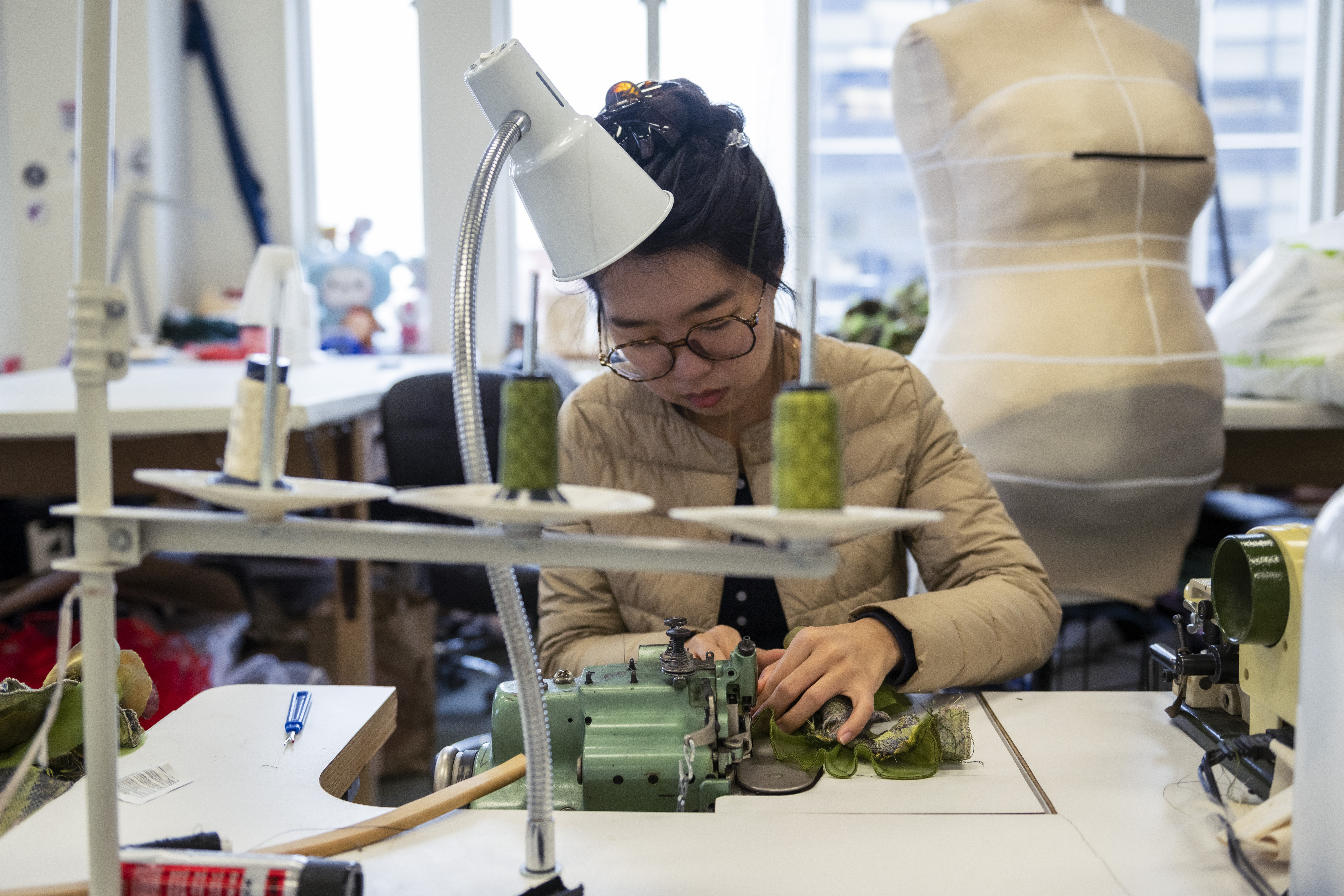 A costume design student sits working at a sewing machine in the costume studio at the CMU School Of Drama.