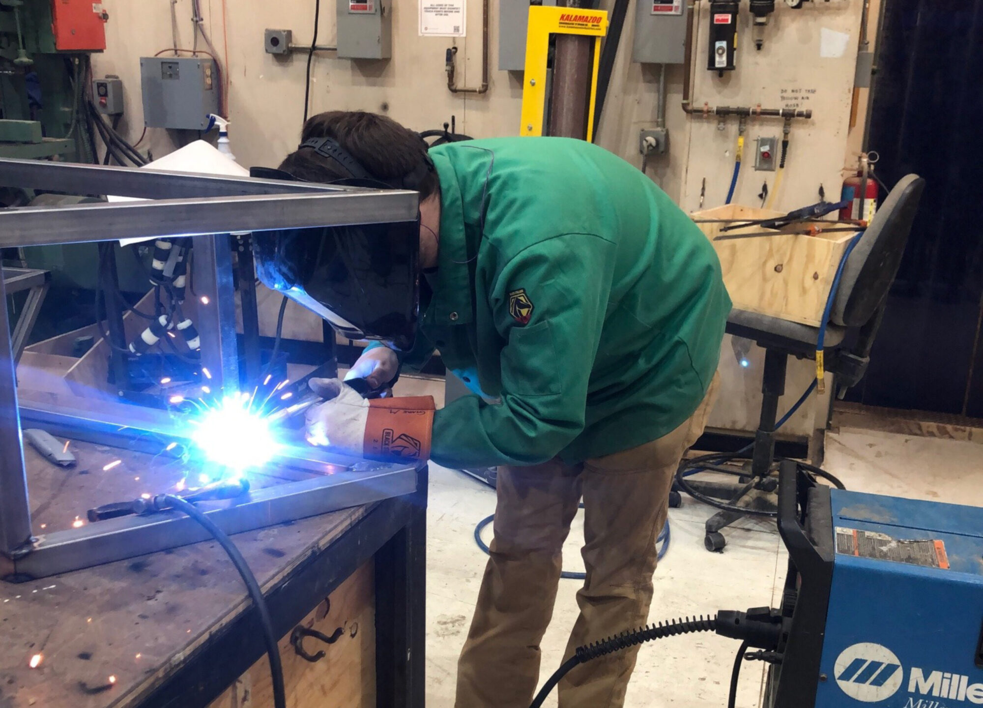 A student wears a protective mask and uses welding equipment in the School of Drama’s scene shop.