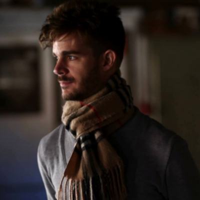 Photo of Adam Thompson - Man with a mustache wearing a scarf, staring into the distance