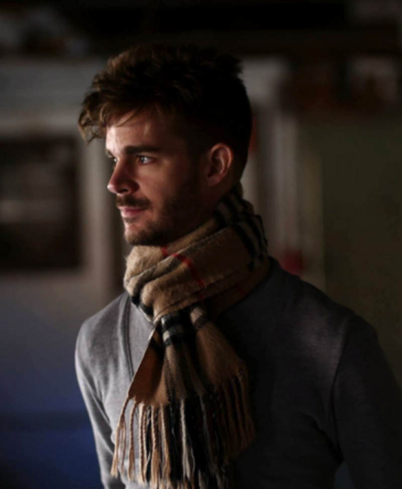 Photo of Adam Thompson - Man with a mustache wearing a scarf, staring into the distance