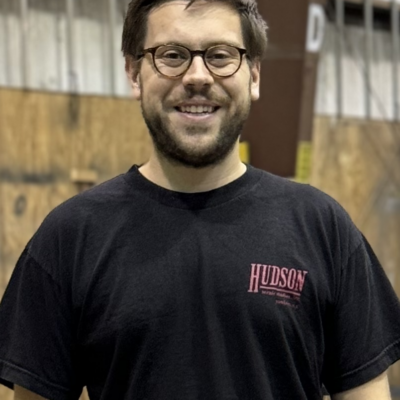 Photo of Ben King - a white man with light brown hair and beard, wearing glasses and a black t-shirt.