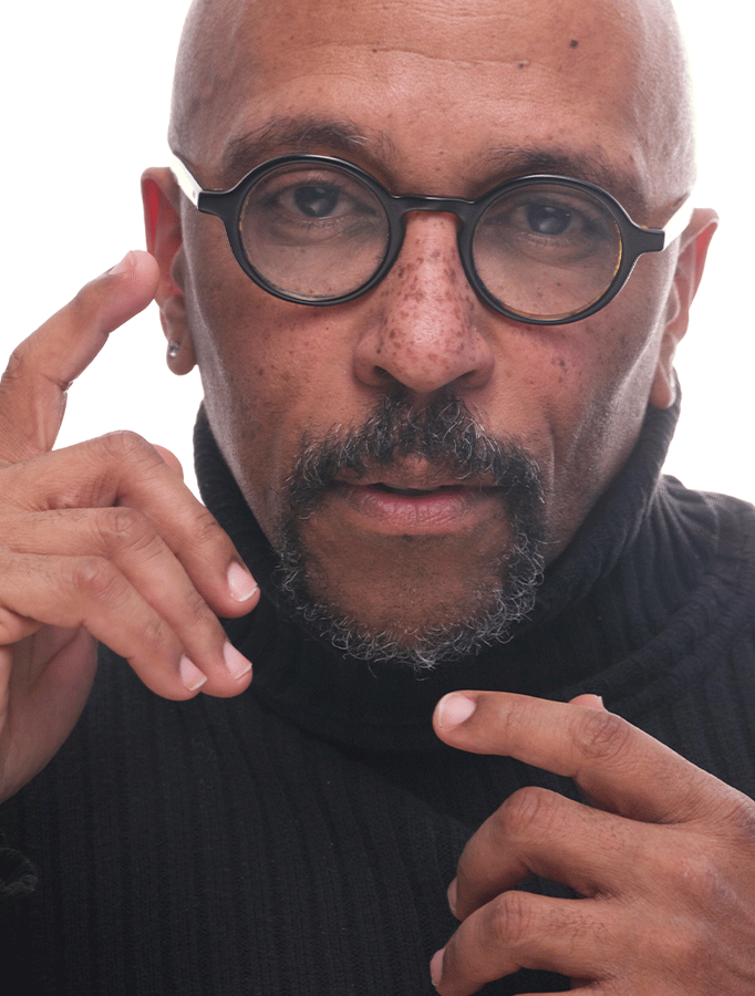 Photo of Tomé Cousin, a Black man with a bald head and round framed glasses, wearing a black turtleneck.