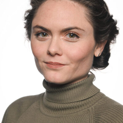 Photo of Danielle Dulchinos, a white woman with brown hair pulled back, wearing an olive green turtleneck sweater.