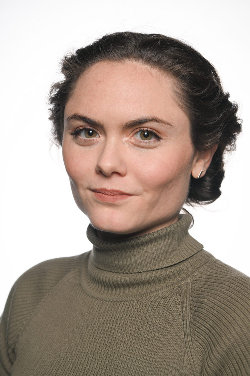 Photo of Danielle Dulchinos, a white woman with brown hair pulled back, wearing an olive green turtleneck sweater.