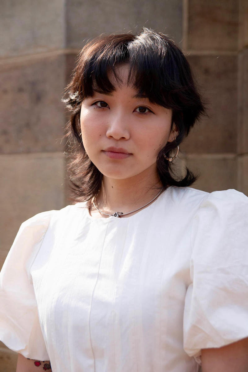 Photo of Davine Byon, a woman with short dark hair wearing a white blouse with puffy short sleeves.