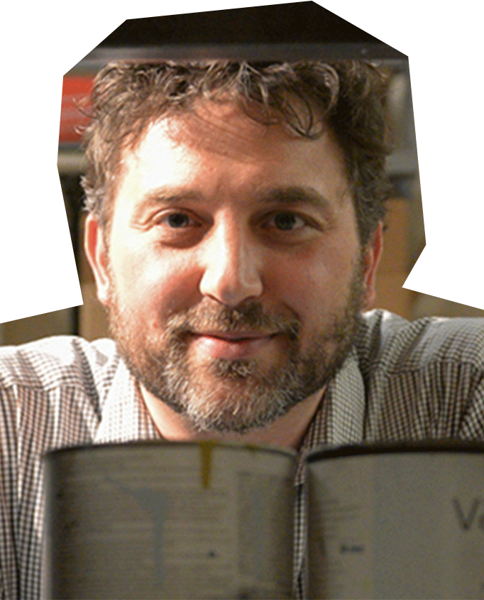 Photo of Gianni Downs, a white man with brown curly hair and short beard.