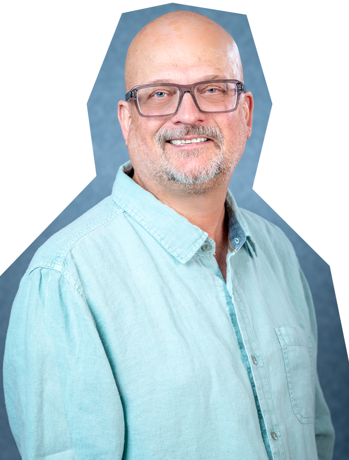 Photo of Hugh Hanson, a white man with a bald head, glasses, and a short gray beard, wearing a light teal button down, collared shirt.