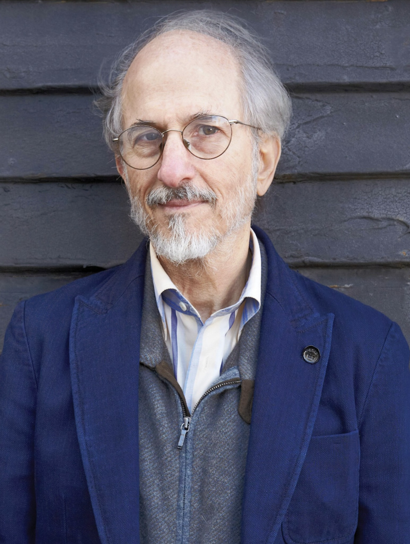 Photo of Jules Fisher, a white man with gray hair, white beard and glasses, wearing a collared shirt, gray zip-up, and navy blazer.