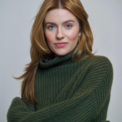 Photo of Kennedy McMann, a white woman with strawberry blonde hair, wearing a green sweater.