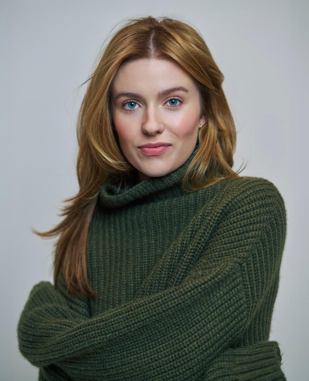 Photo of Kennedy McMann, a white woman with strawberry blonde hair, wearing a green sweater.