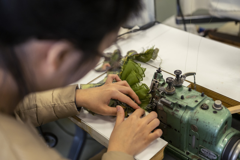 A student works on finishing the edges of a costume project on a machine in CMU's Costume Studio.