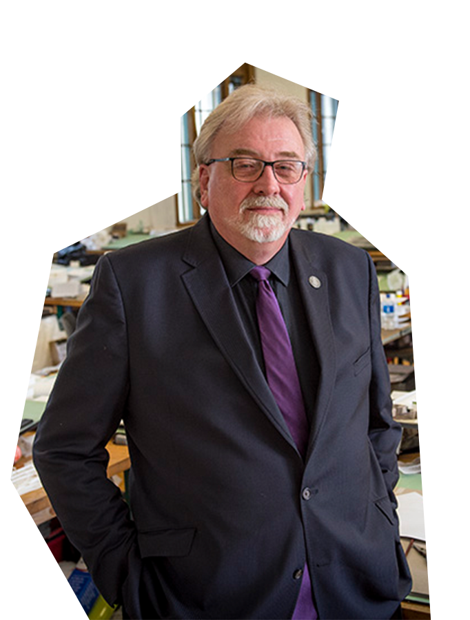 Photo of Dan Martin, a tall white man with white hair and beard, wearing glasses and a dark suit and purple tie.