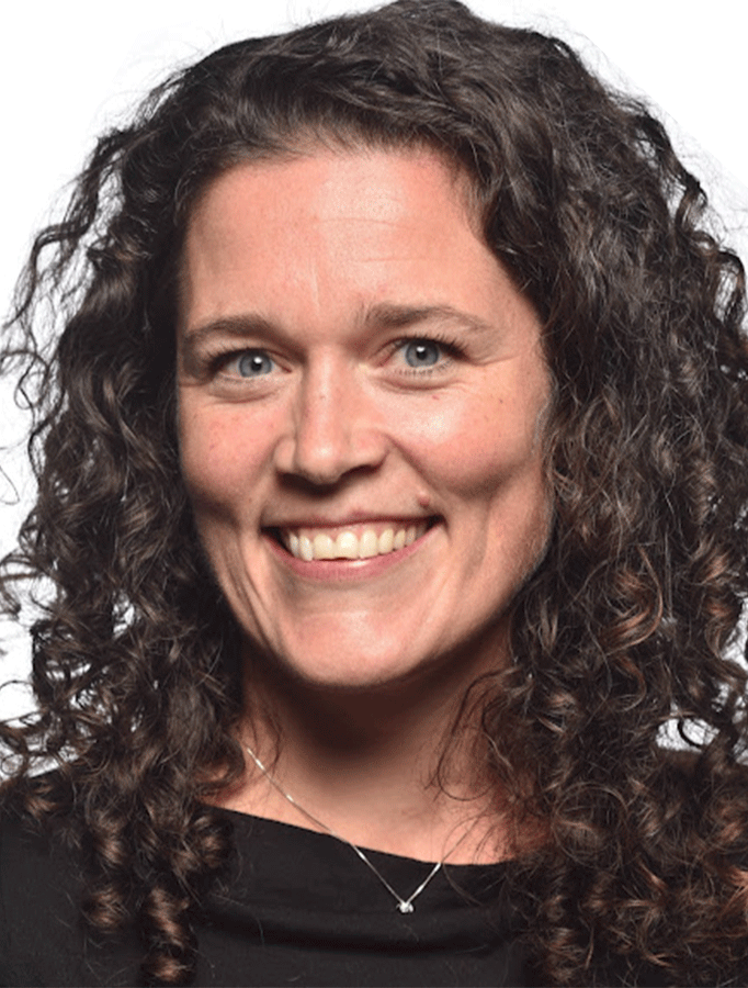 Headshot of Amy Nichols, a white woman with long curly dark brown hair, wearing a black shirt.