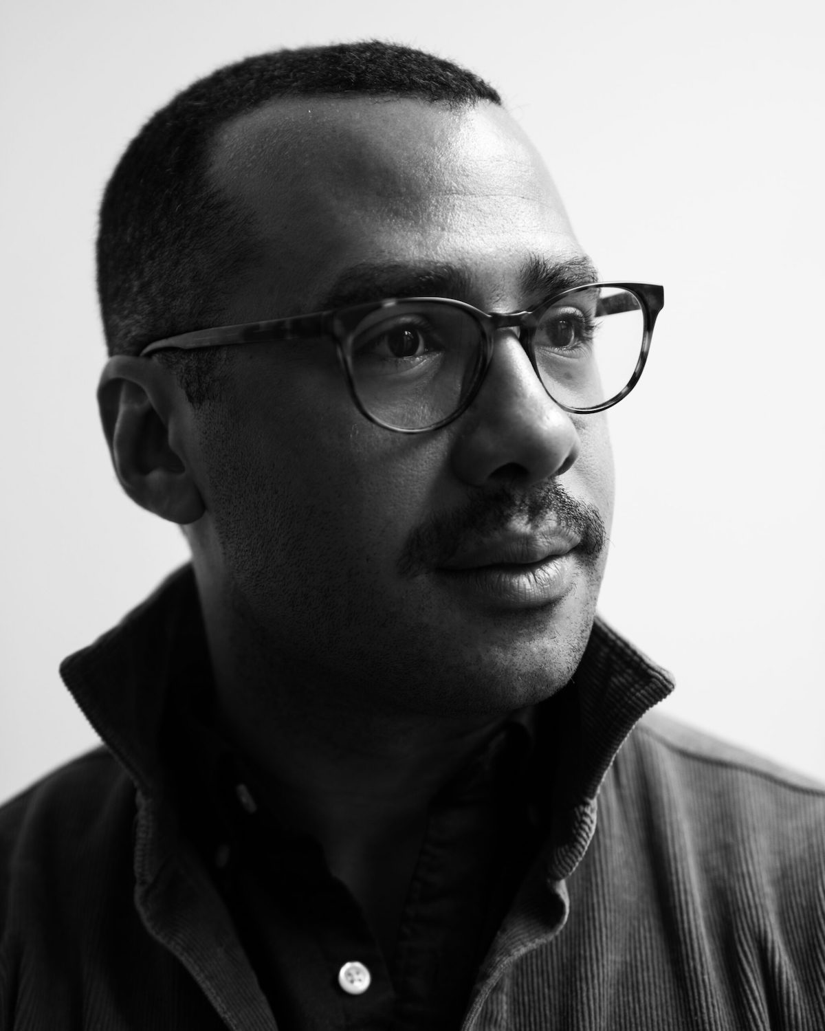 Black and white photo of Peter Andersen, a man with short dark hair and glasses, wearing a corduroy jacket with a popped collar.