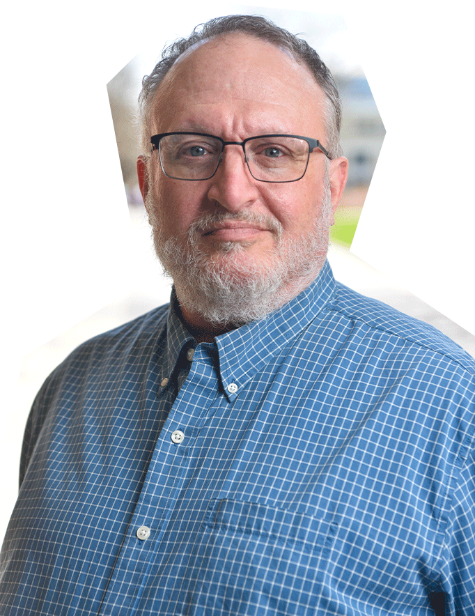 Photo of Joe Pino, a white man with short gray hair and beard, wearing glasses and a blue button down shirt.