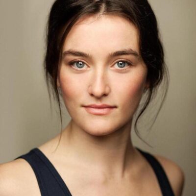 Photo of Sarah Pidgeon, a white woman with brown hair, pulled back, wearing a black tank top.