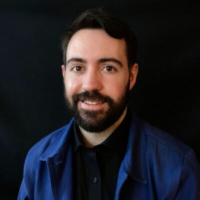 Photo of Sean Byrum Leo - a bearded man wearing blue dress shirt over a black t-shirt