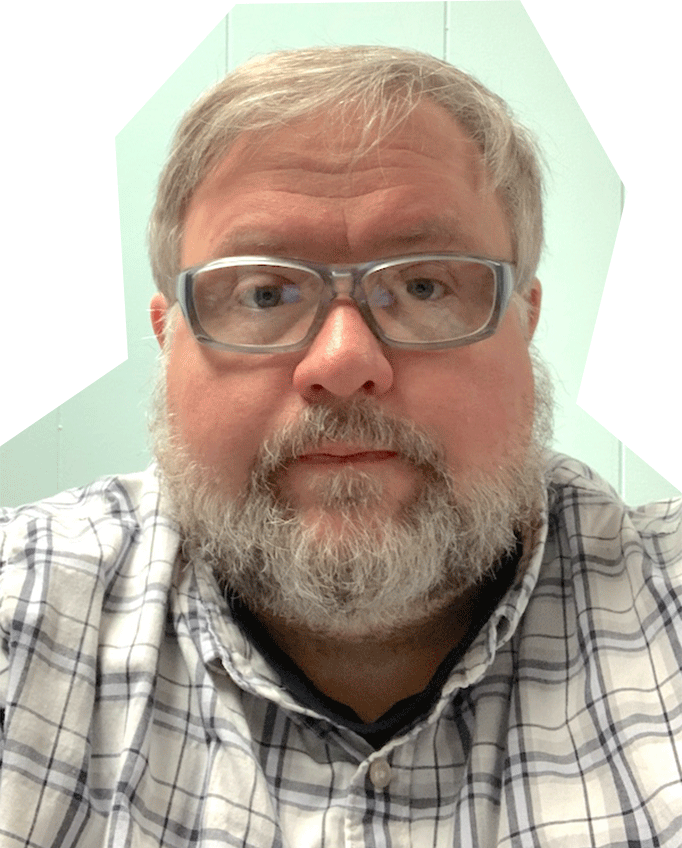 Photo of Sean West, a white man with gray hair and beard, wearing glasses and a white checkered shirt.