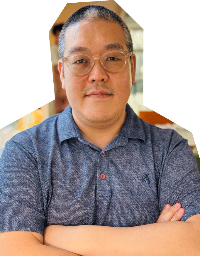 Photo of Yong Suk Yoo, an Asian man with short dark har and glasses, wearing a blue short-sleeved, collared shirt, crossing his arms at his chest and smiling.