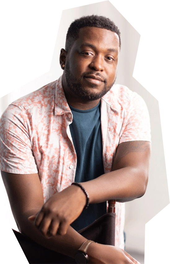 Photo of TJ Young, a Black man with short black hair wearing a coral colored, short-sleeved collared shirt with a floral pattern, unbuttoned over a gray t-shirt.