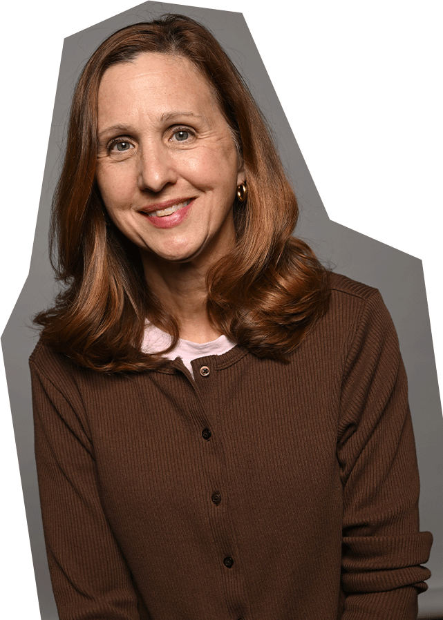 Photo of Beth Zamborsky, a white woman with long red/brown hair, wearing a brown sweater and smiling.