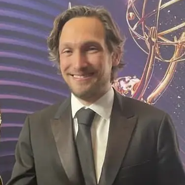 Photo of Noah Mitz, a white man with dirty blonde hair, wearing a suit and tie at the Emmy Awards.