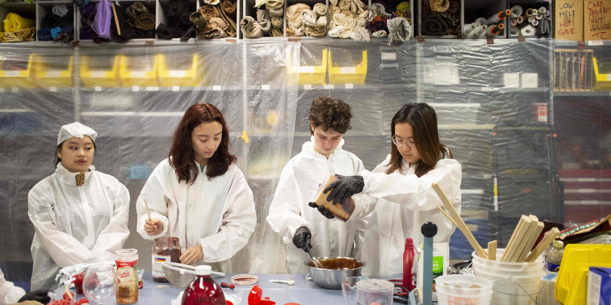 Four students in white lab coats make fake blood in the CMU Prop Shop