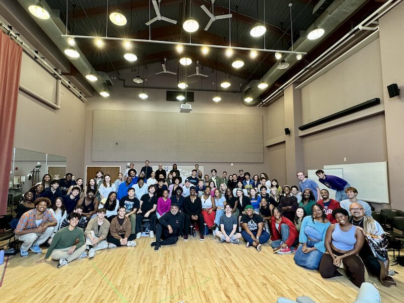 Large group of students and faculty pose for a photo with Leslie Odom, Jr. in an acting classroom.