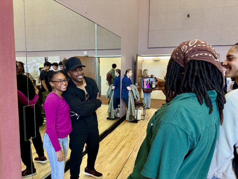 Leslie Odom, Jr. poses for a photo with a student in an acting classroom.