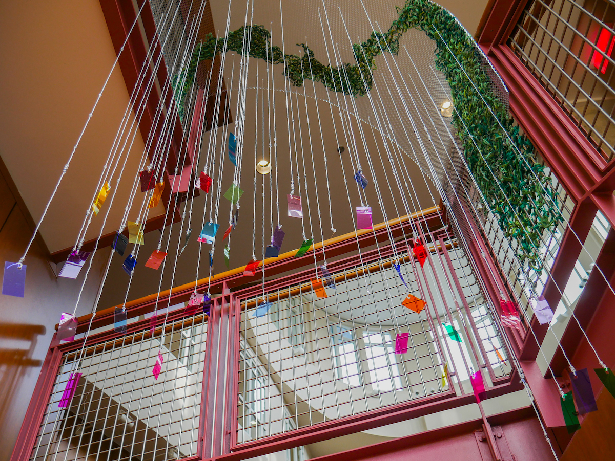 Small, colorful geometric shapes hang from stings from the ceiling above the staircase in Purnell Center for the Arts.