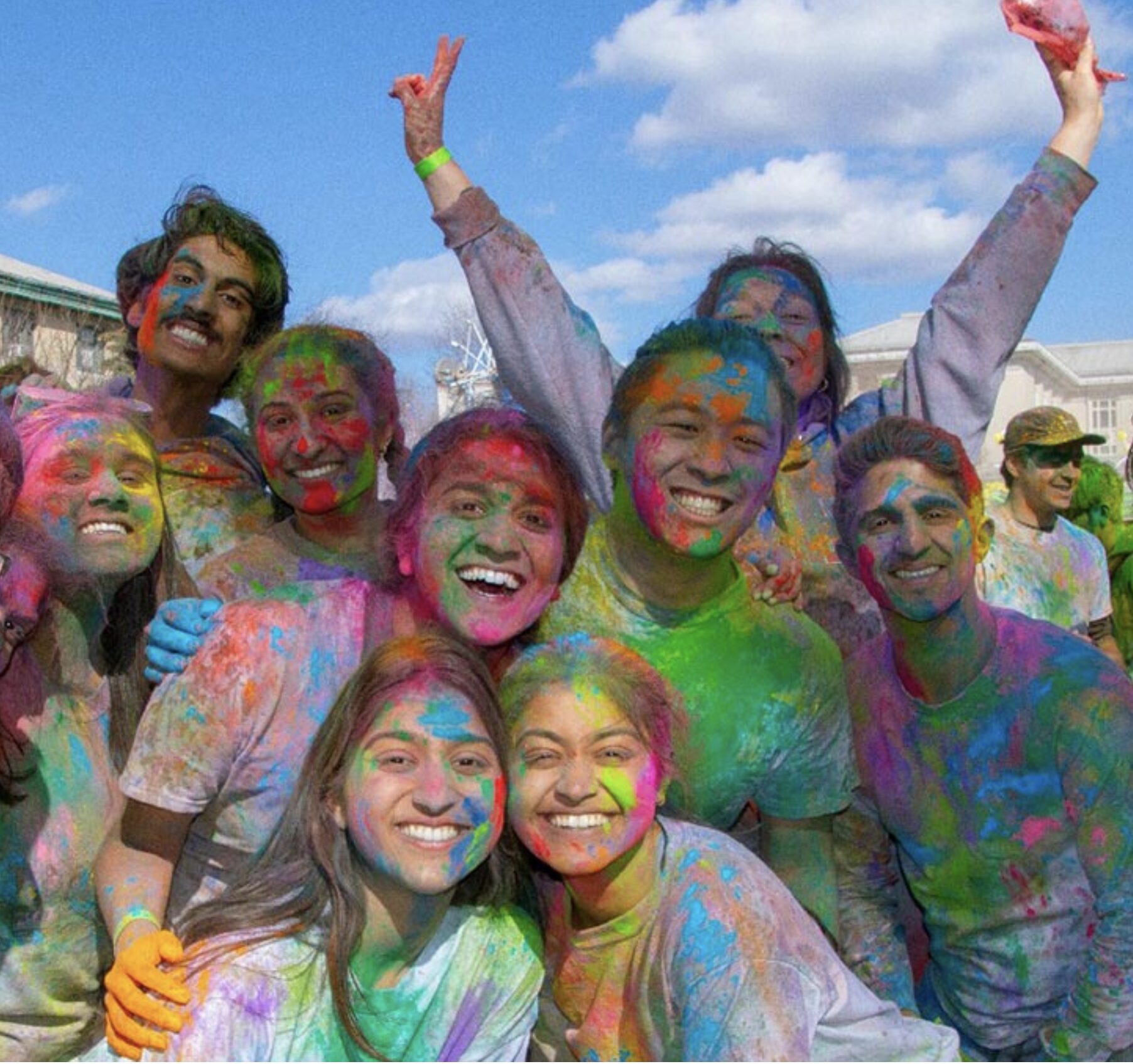 A group of students with colorful powders on their faces and clothes.