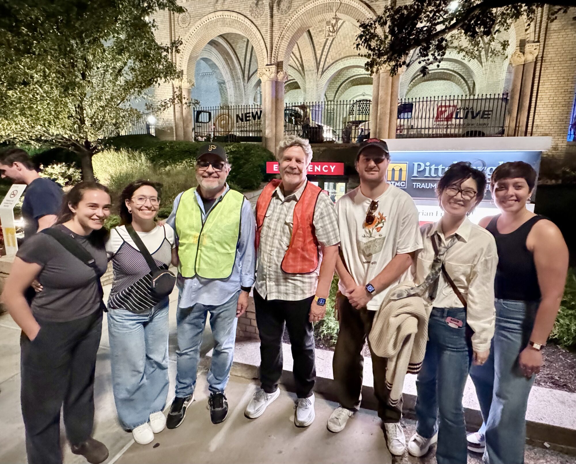 Directing students stand with John Wells and Michael Hissrich on the set of "The Pitt" on location in Pittsburgh.